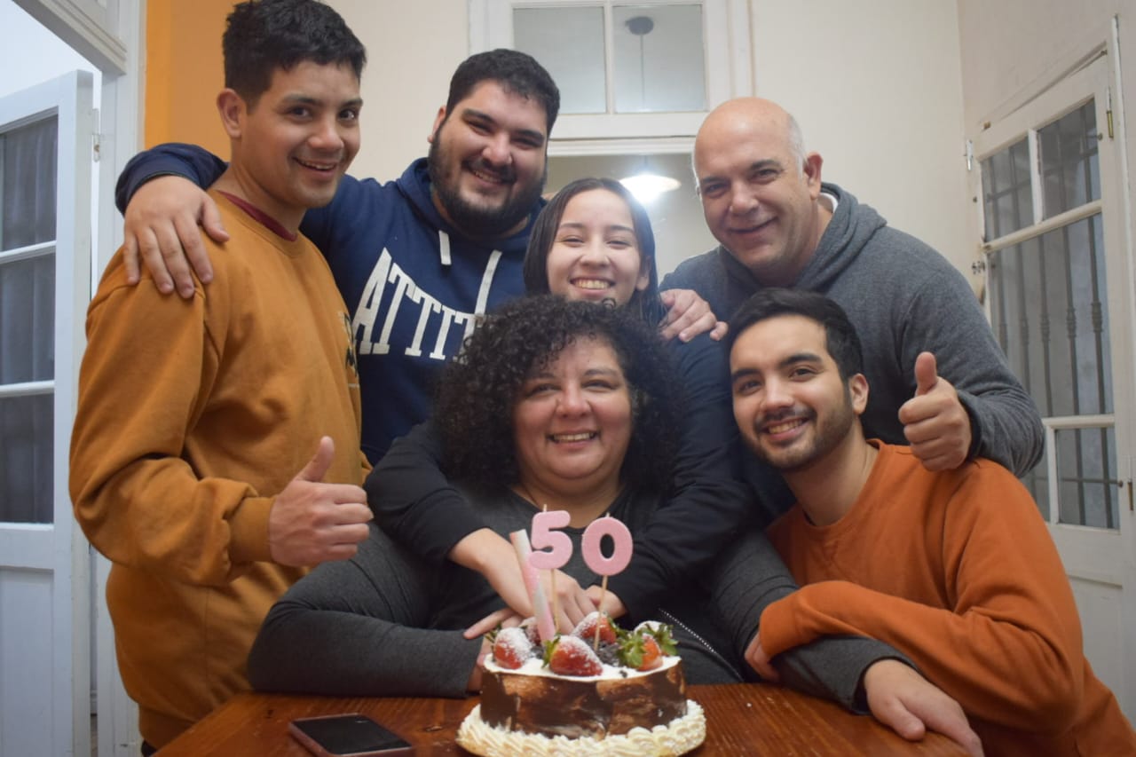 Foto de una familia abrazados festejando los 50 años de la madre